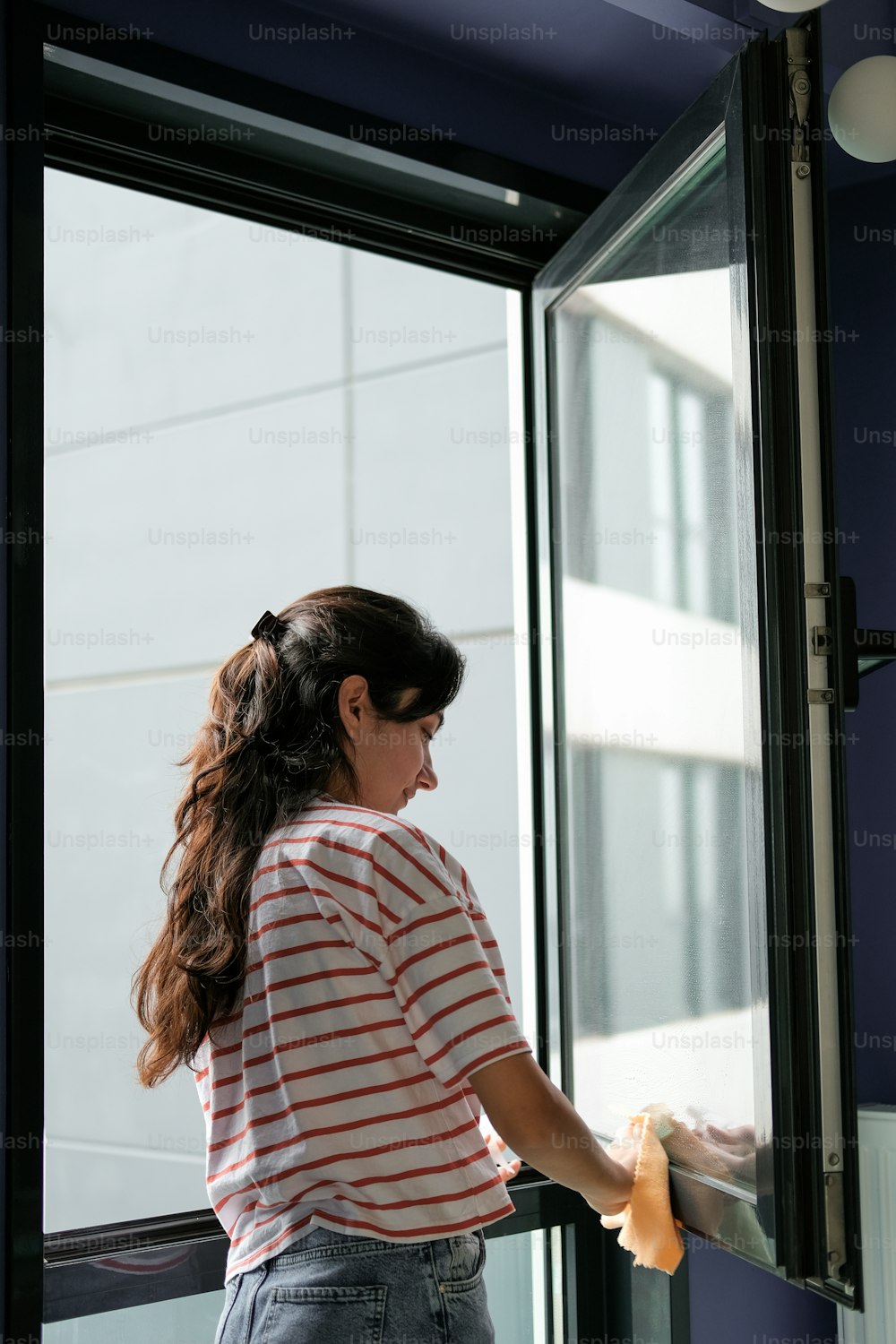 Una mujer con camisa a rayas abriendo una puerta de vidrio