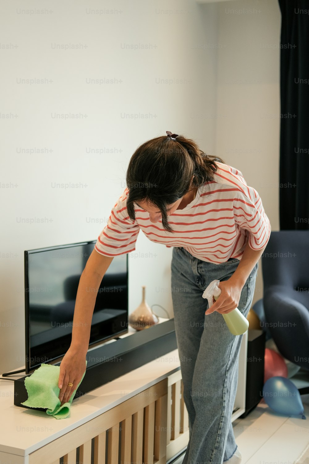 Eine Frau putzt einen Fernseher mit einem Tuch
