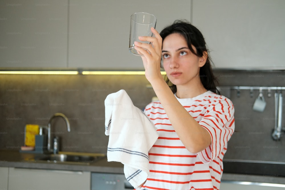 Una mujer sosteniendo un vaso de agua en una cocina