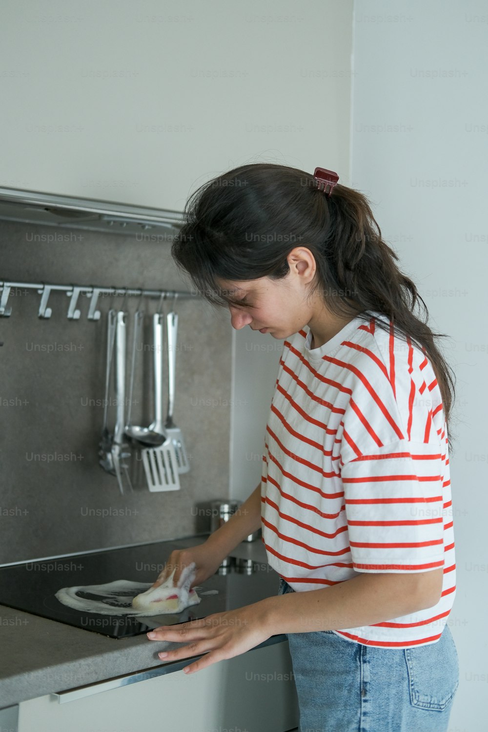 Una mujer lavando platos en un fregadero de cocina