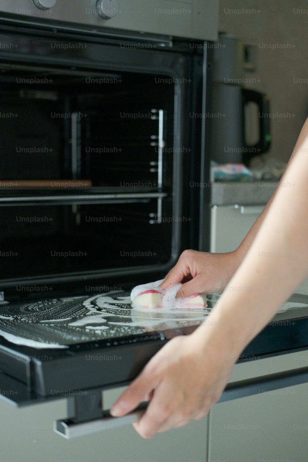 a person cleaning a stove with a rag