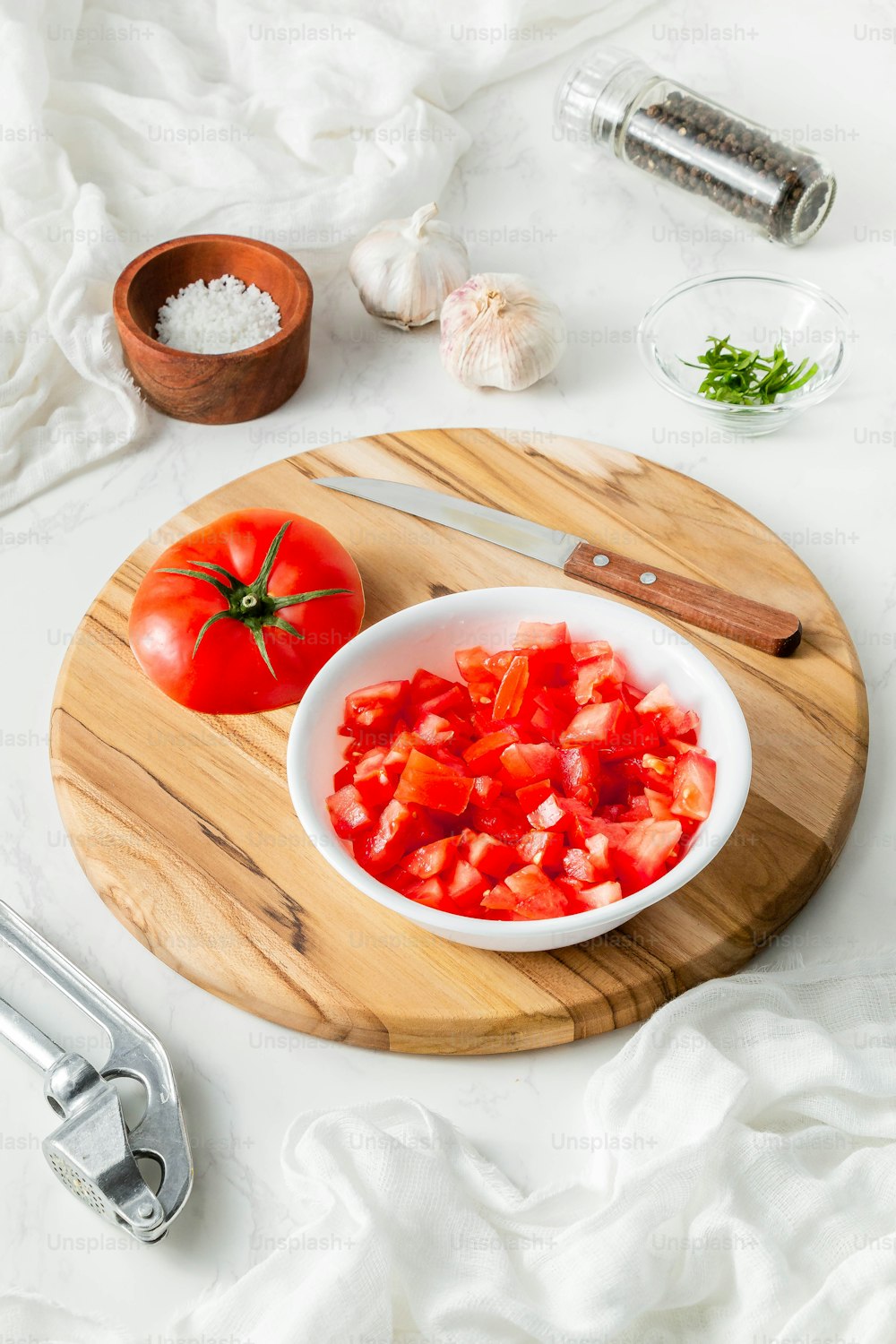 a wooden cutting board topped with a bowl of chopped tomatoes