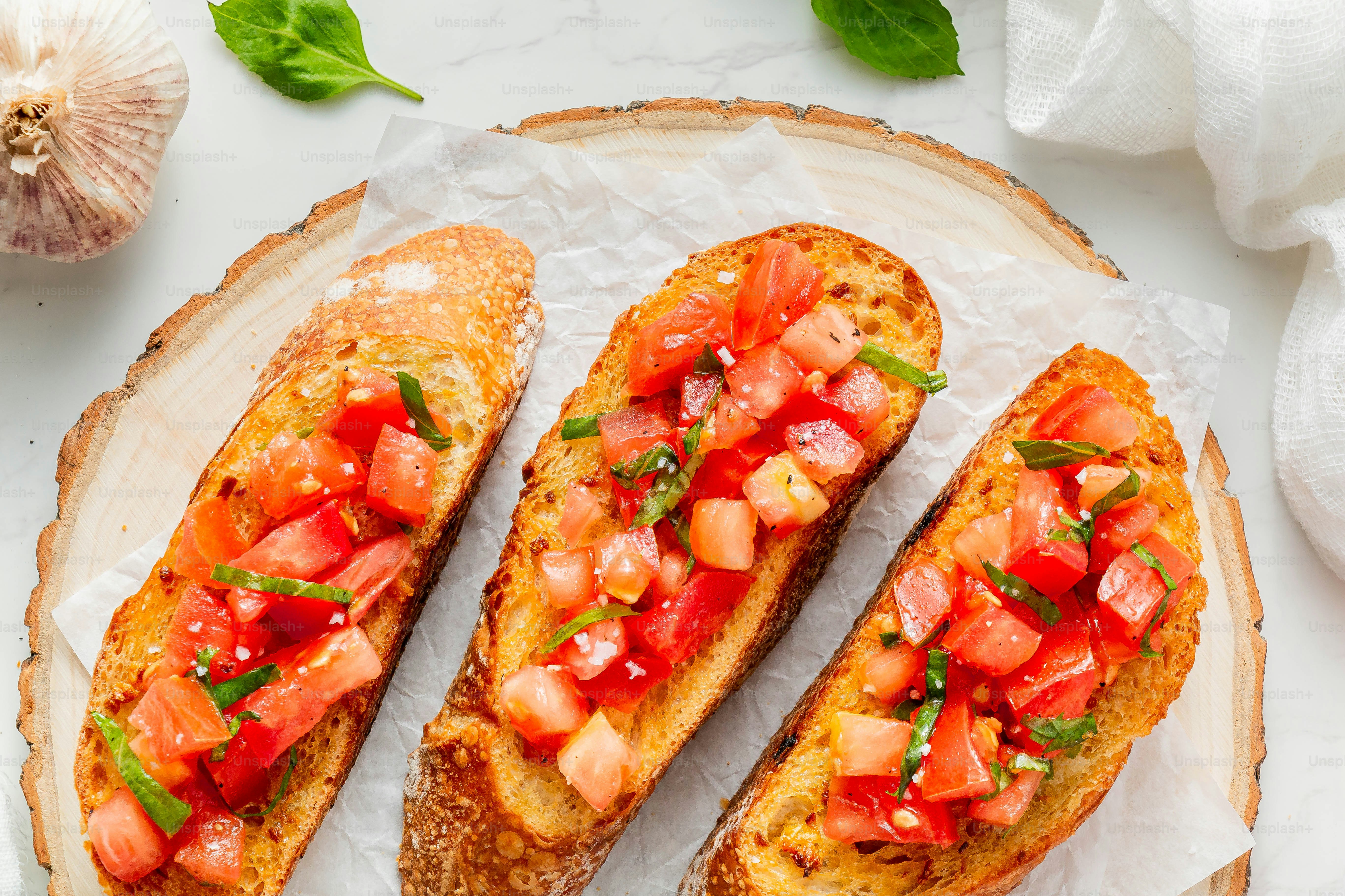 drei Scheiben Brot mit Tomaten und Basilikum oben drauf