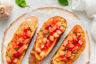 three slices of bread with tomatoes and basil on top