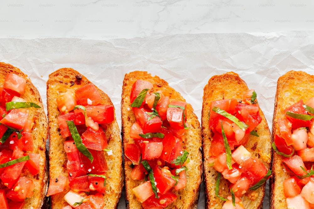 four pieces of bread with tomatoes and basil on them
