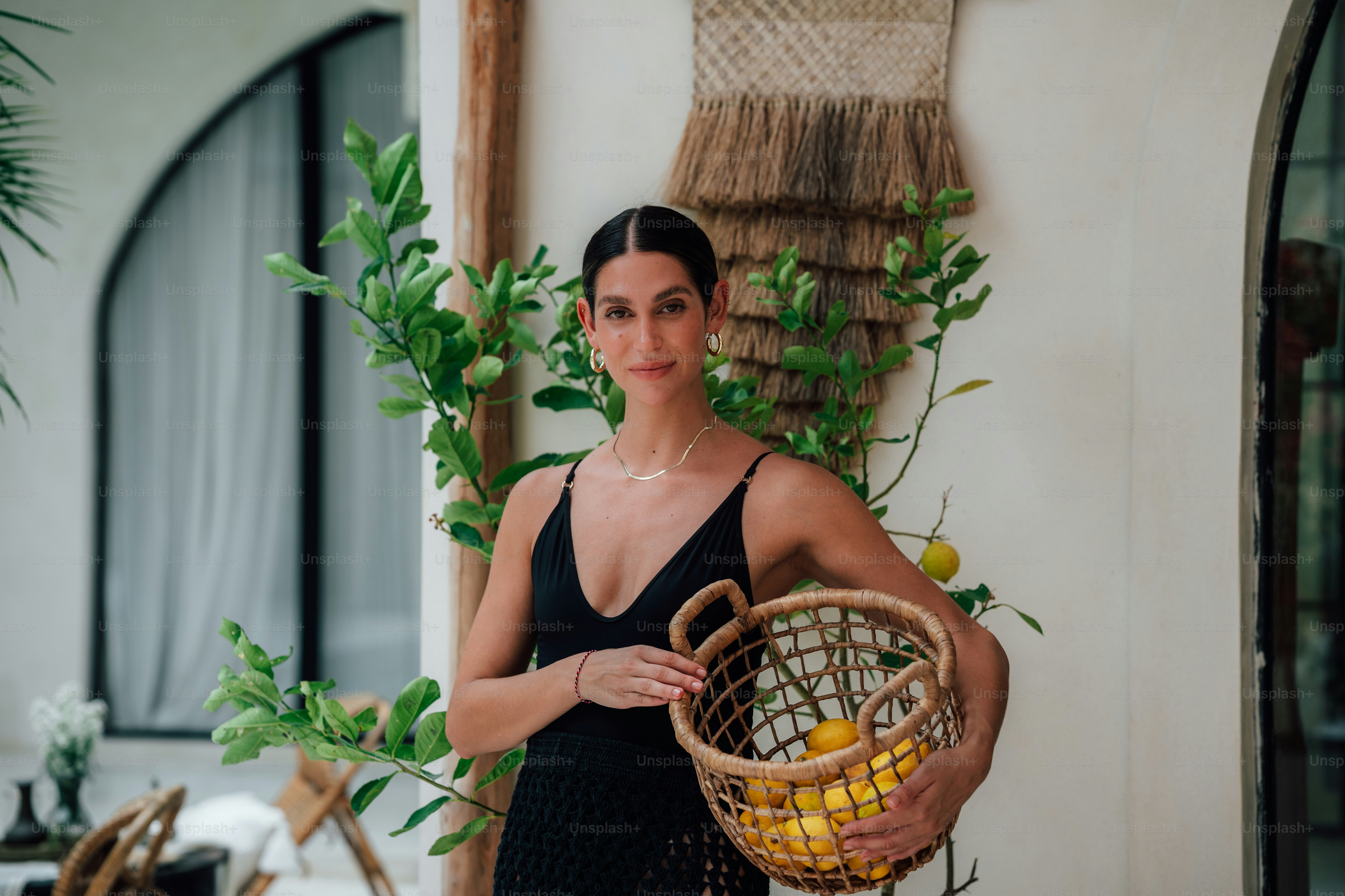 a woman in a black dress holding a basket of fruit