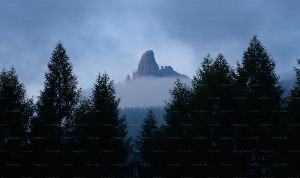 Une haute montagne entourée d’arbres sous un ciel nuageux