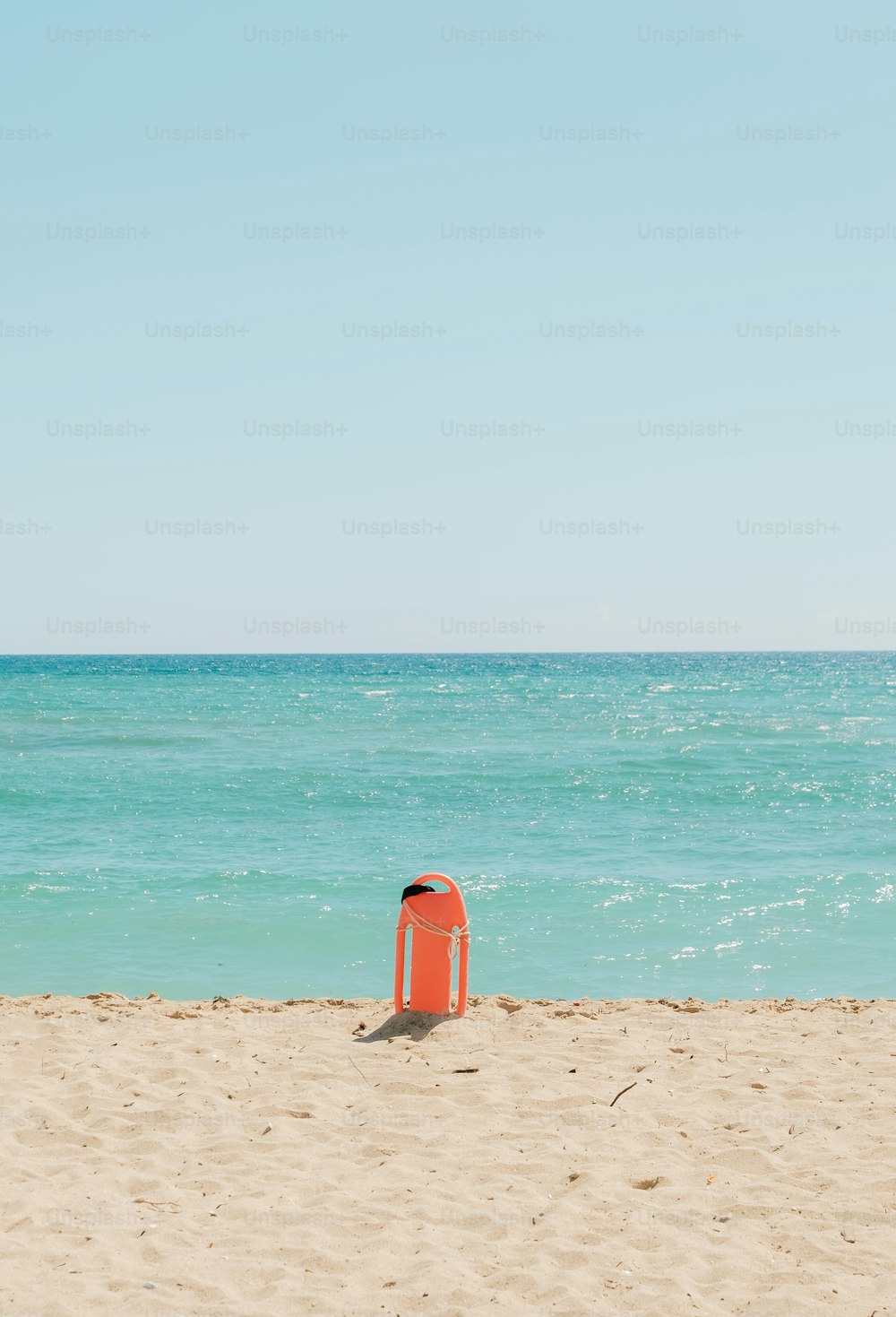 una sedia rossa seduta sulla cima di una spiaggia sabbiosa