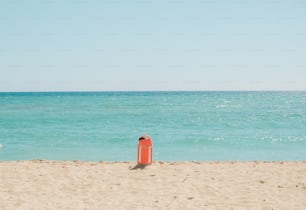 uma boia vermelha sentada em cima de uma praia de areia