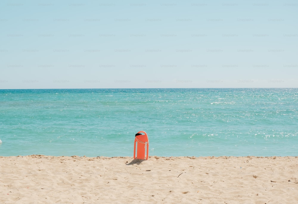 a red buoy sitting on top of a sandy beach
