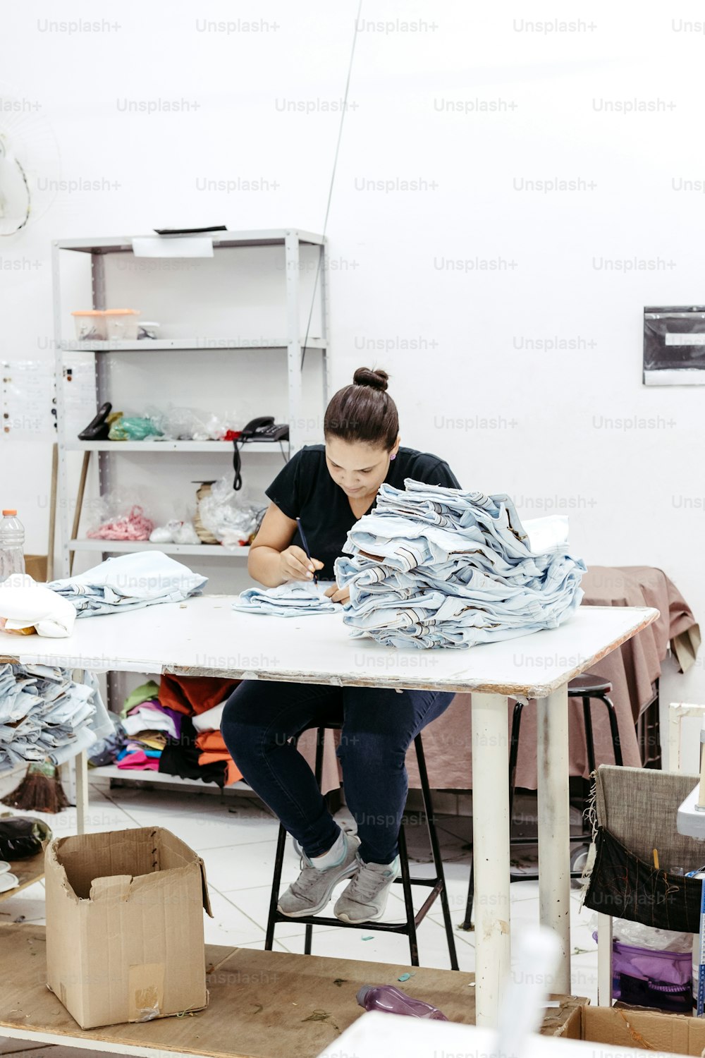 a woman sitting at a table working on a piece of paper