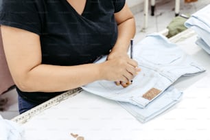 a woman sitting at a table with a pair of jeans on it