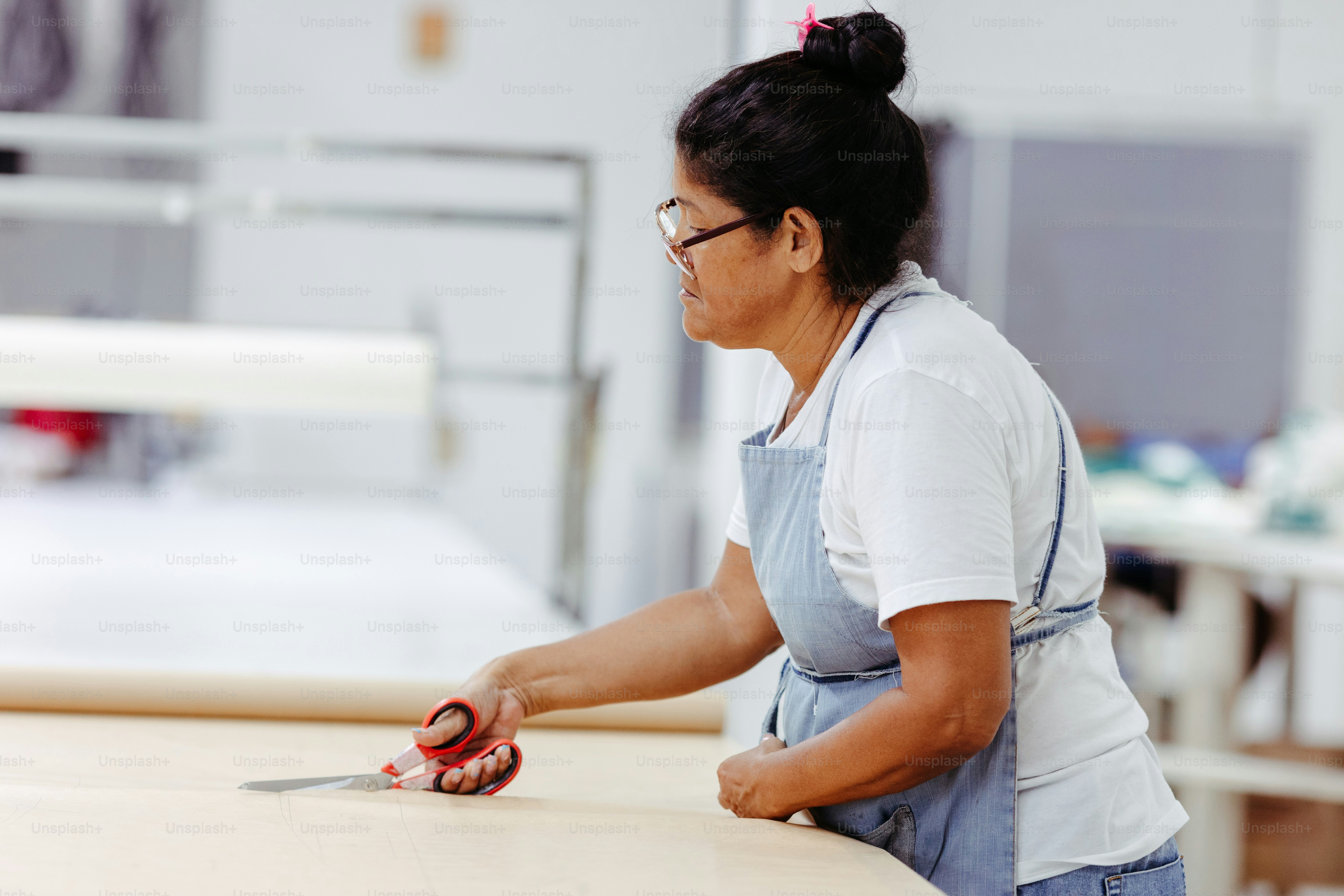 A woman with a pair of scissors on a table photo – Cutting Image on ...