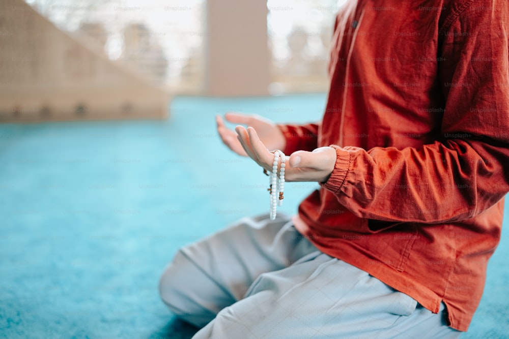 a person sitting on the floor with a rosary in their hand