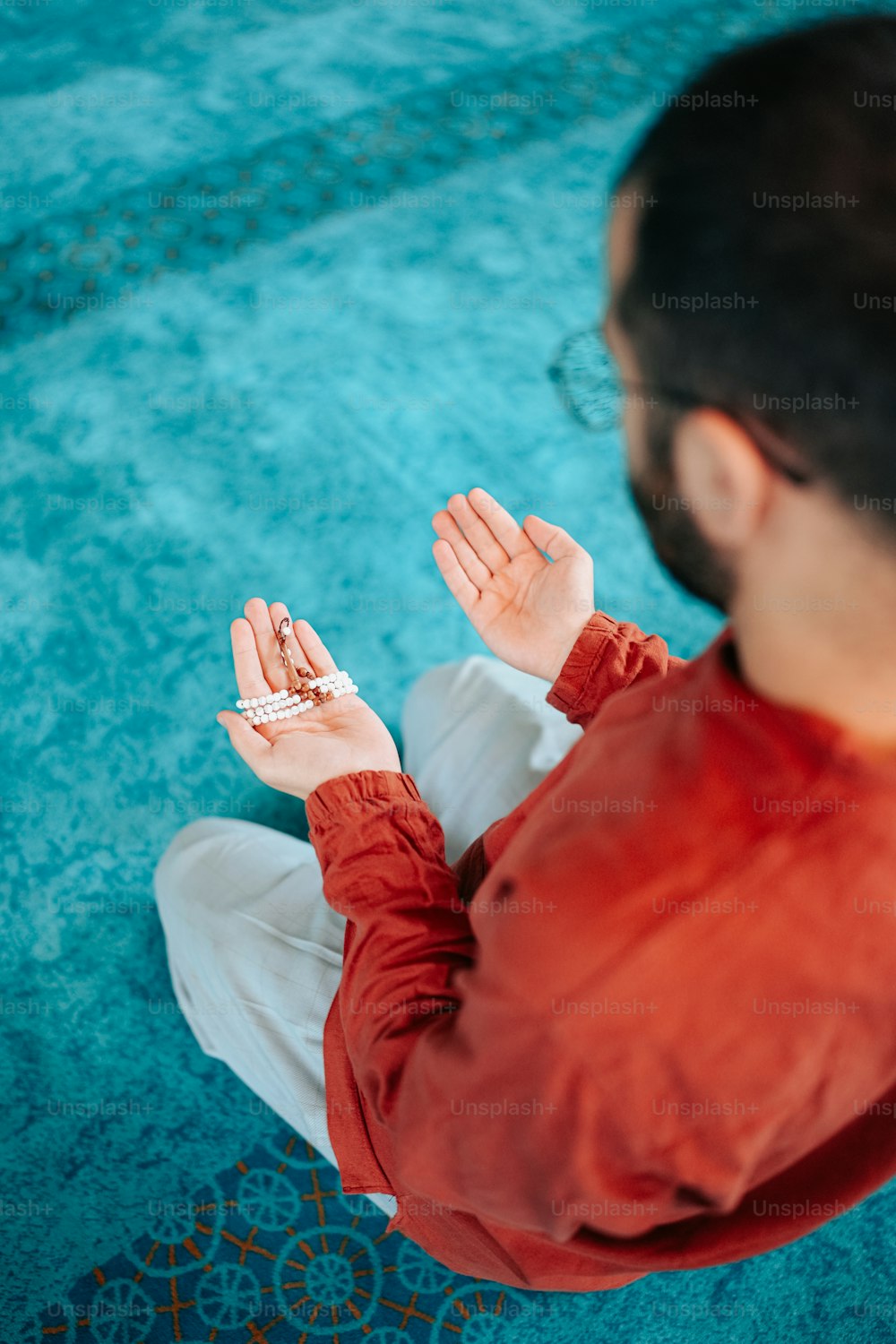 a person sitting on the ground with their hands together