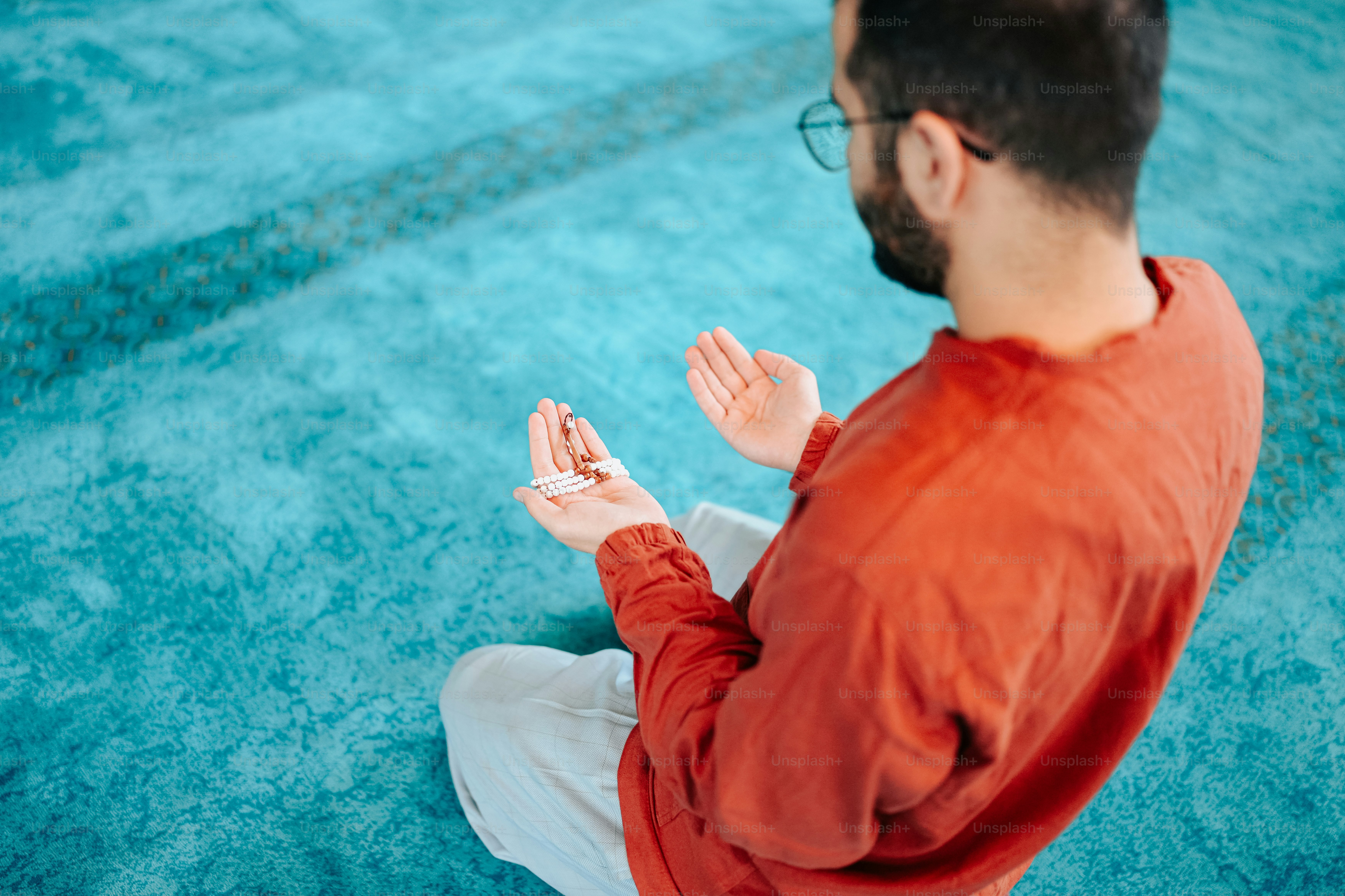 a man sitting on the floor with his hands together