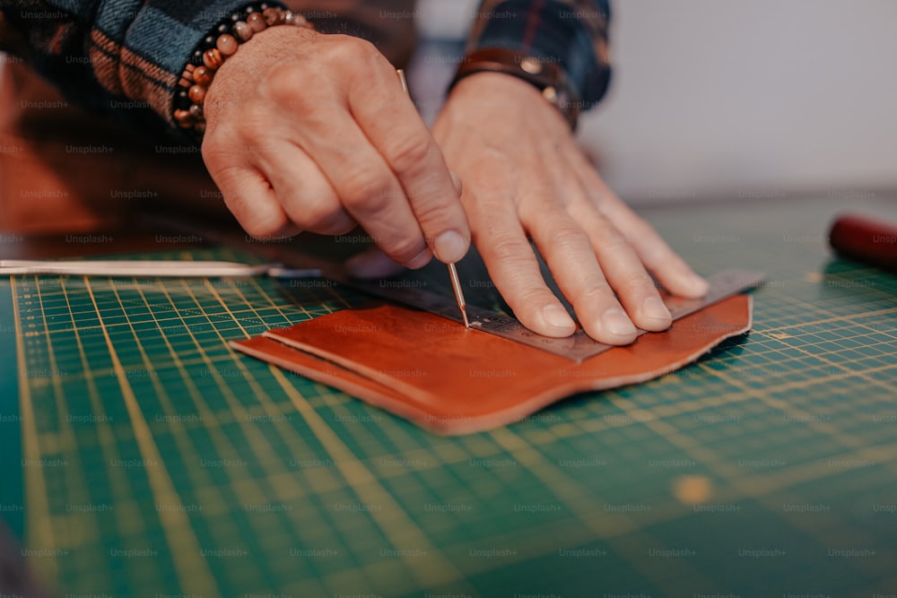 a person cutting a piece of leather with a pair of scissors