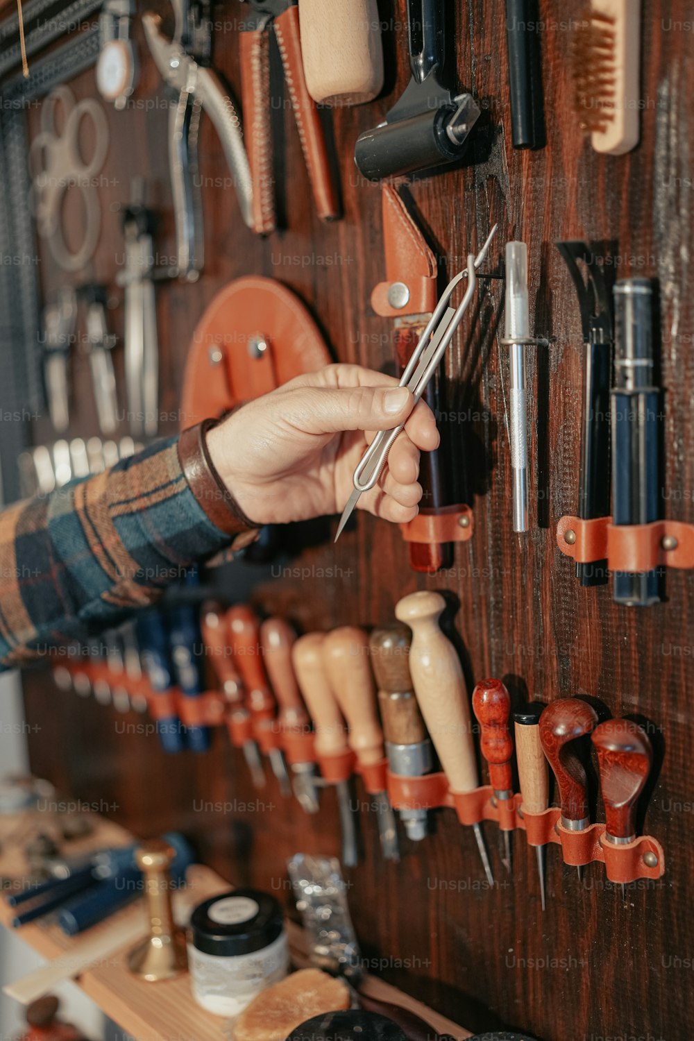 uma pessoa segurando um par de tesouras na frente de uma parede de ferramentas