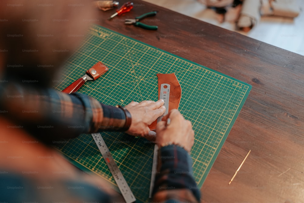 a person cutting a piece of leather with a pair of scissors