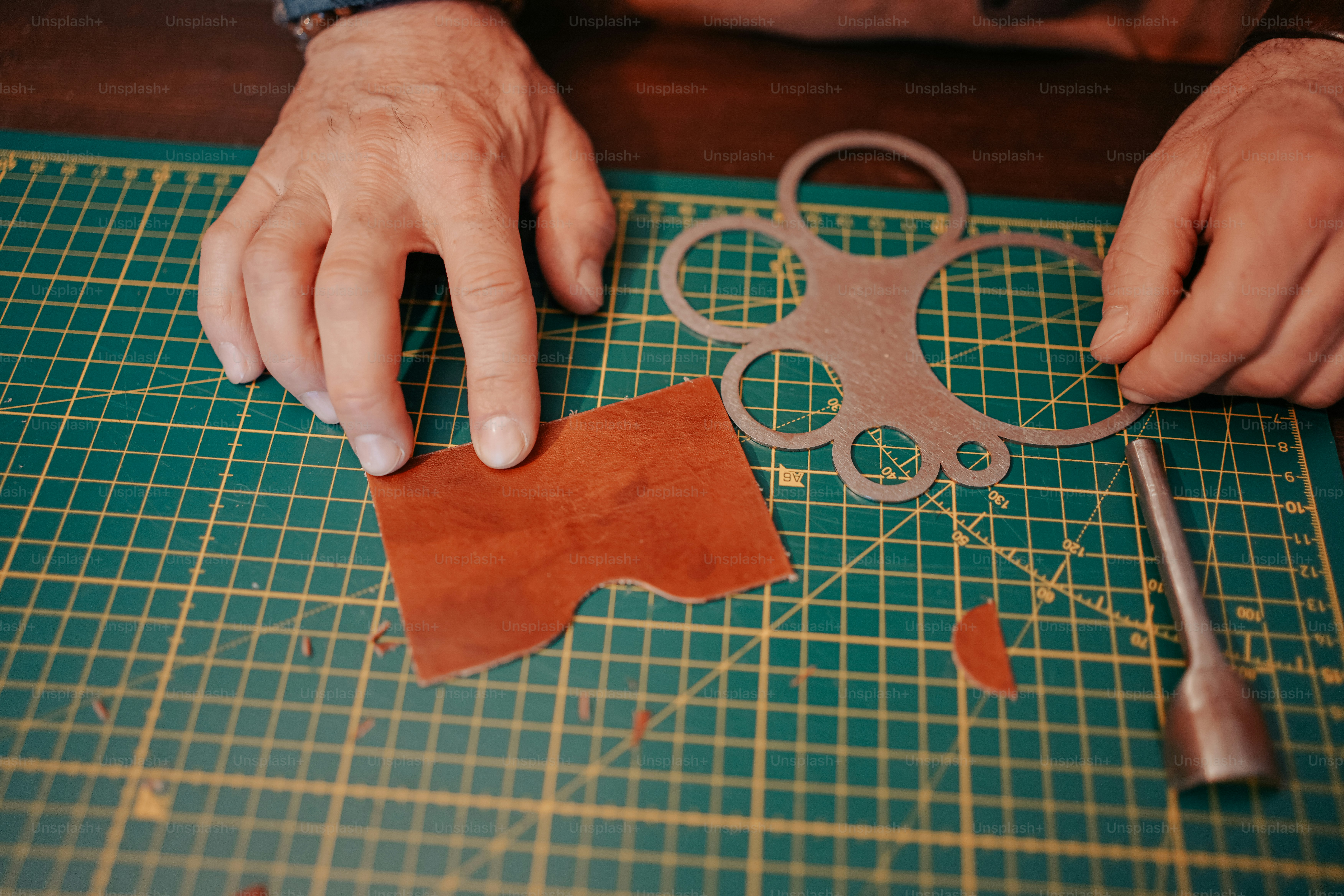 a person cutting a piece of leather with a pair of scissors