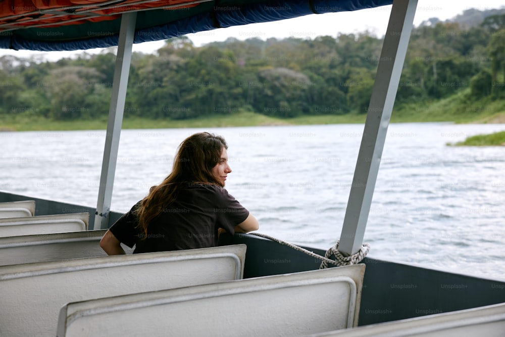 uma mulher sentada na parte de trás de um barco em um lago