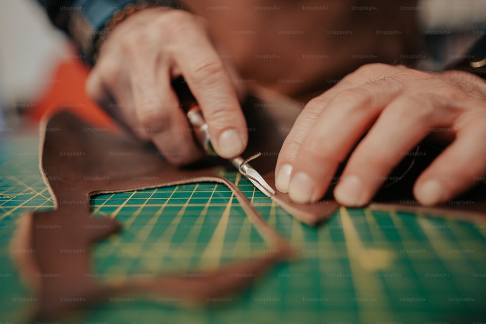 a person cutting a piece of leather with a pair of scissors