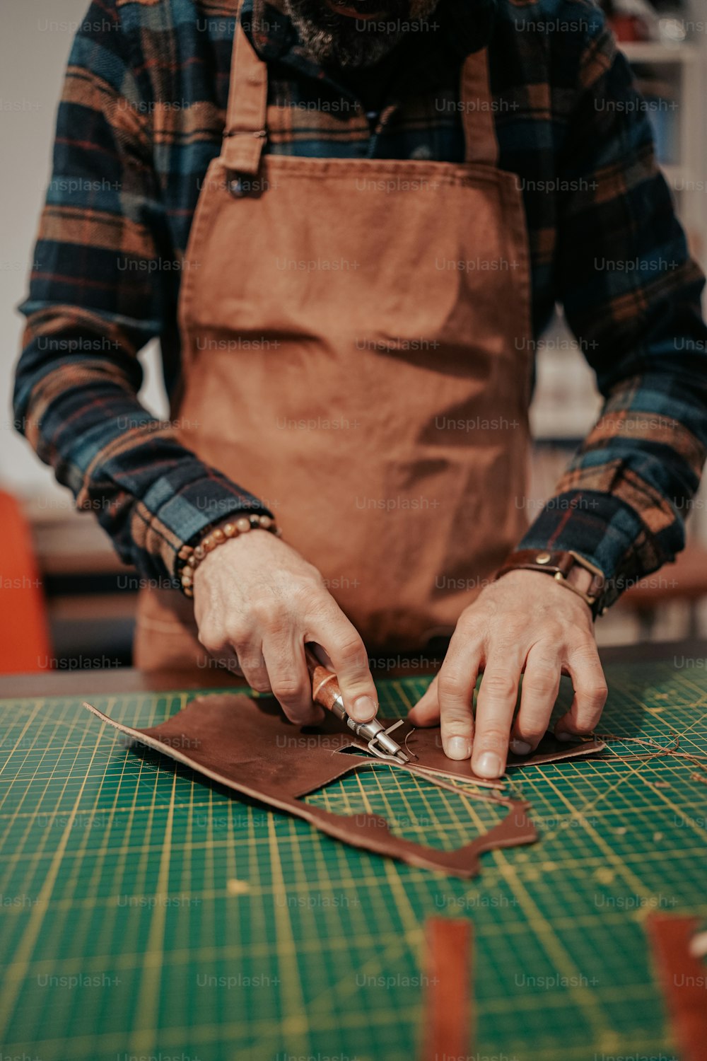 a man cutting a piece of leather with a pair of scissors