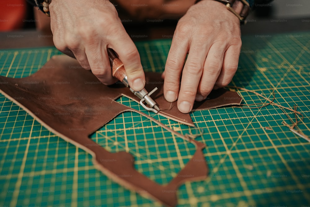 a person cutting leather with a pair of scissors