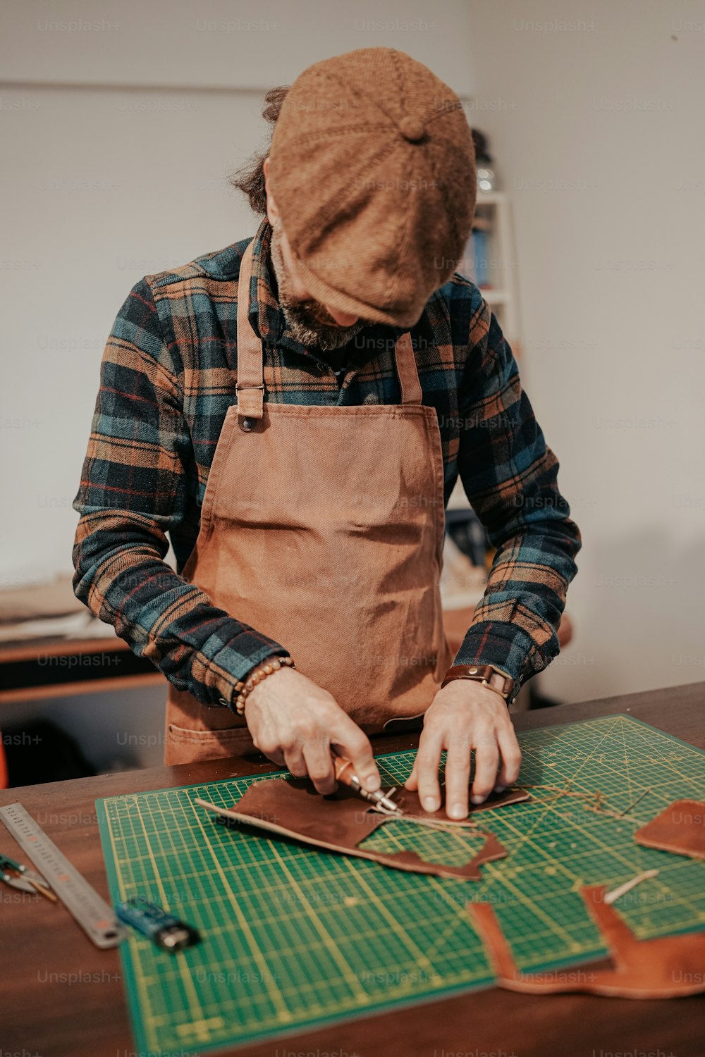a man in an apron cutting up a piece of leather