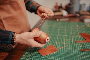 a person using a pair of scissors on a piece of leather