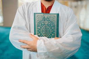 a man in a white robe holding a green book