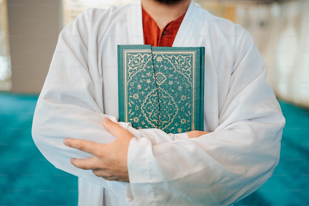 a man in a white robe holding a green book