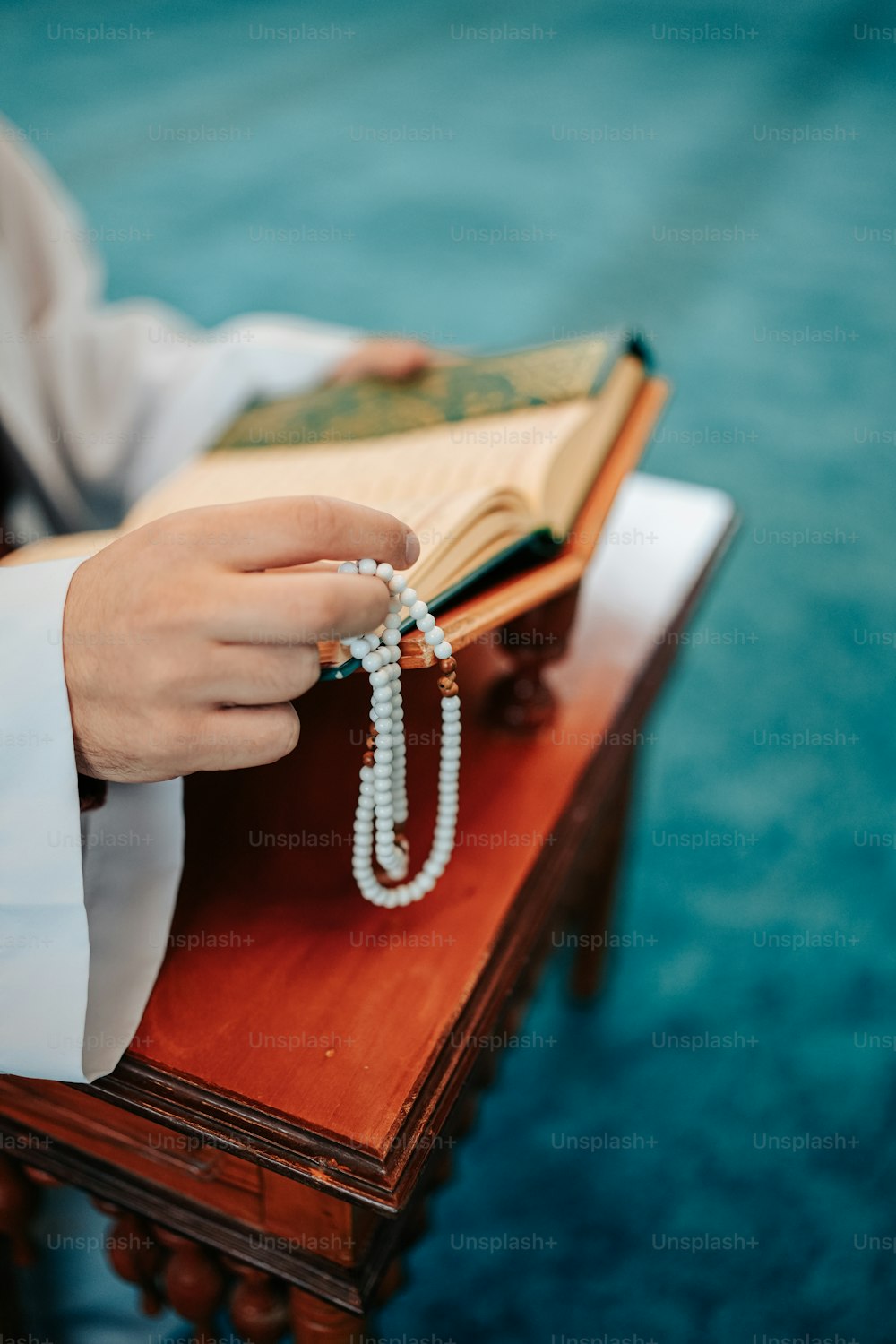 a person holding a rosary on top of a wooden table