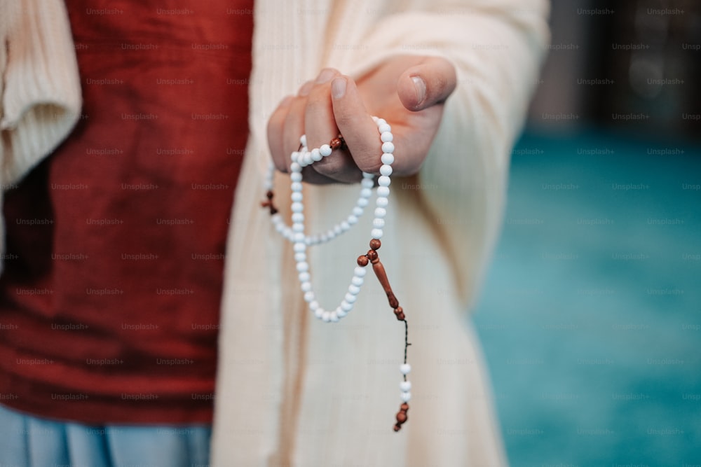 una persona sosteniendo un rosario en la mano