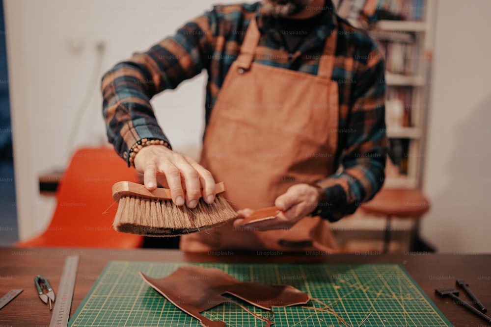 a man with an apron and a brush on a table