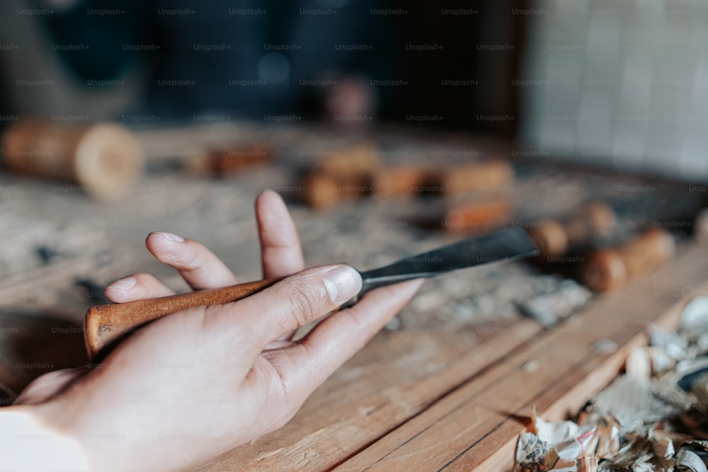 a person holding a knife on top of a wooden table