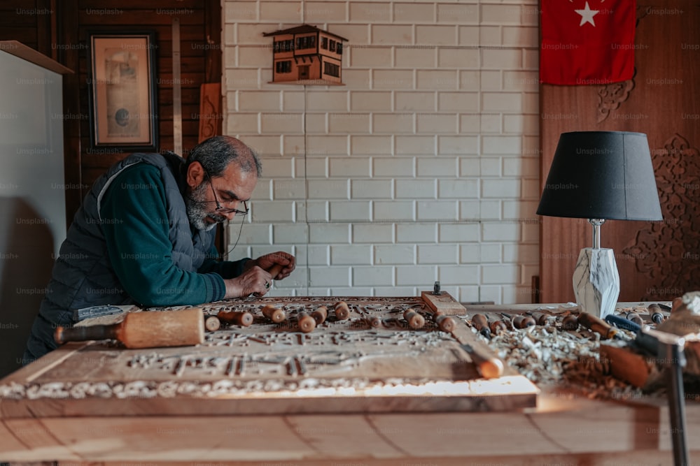 Ein Mann sitzt an einem Tisch und arbeitet an einem Stück Holz