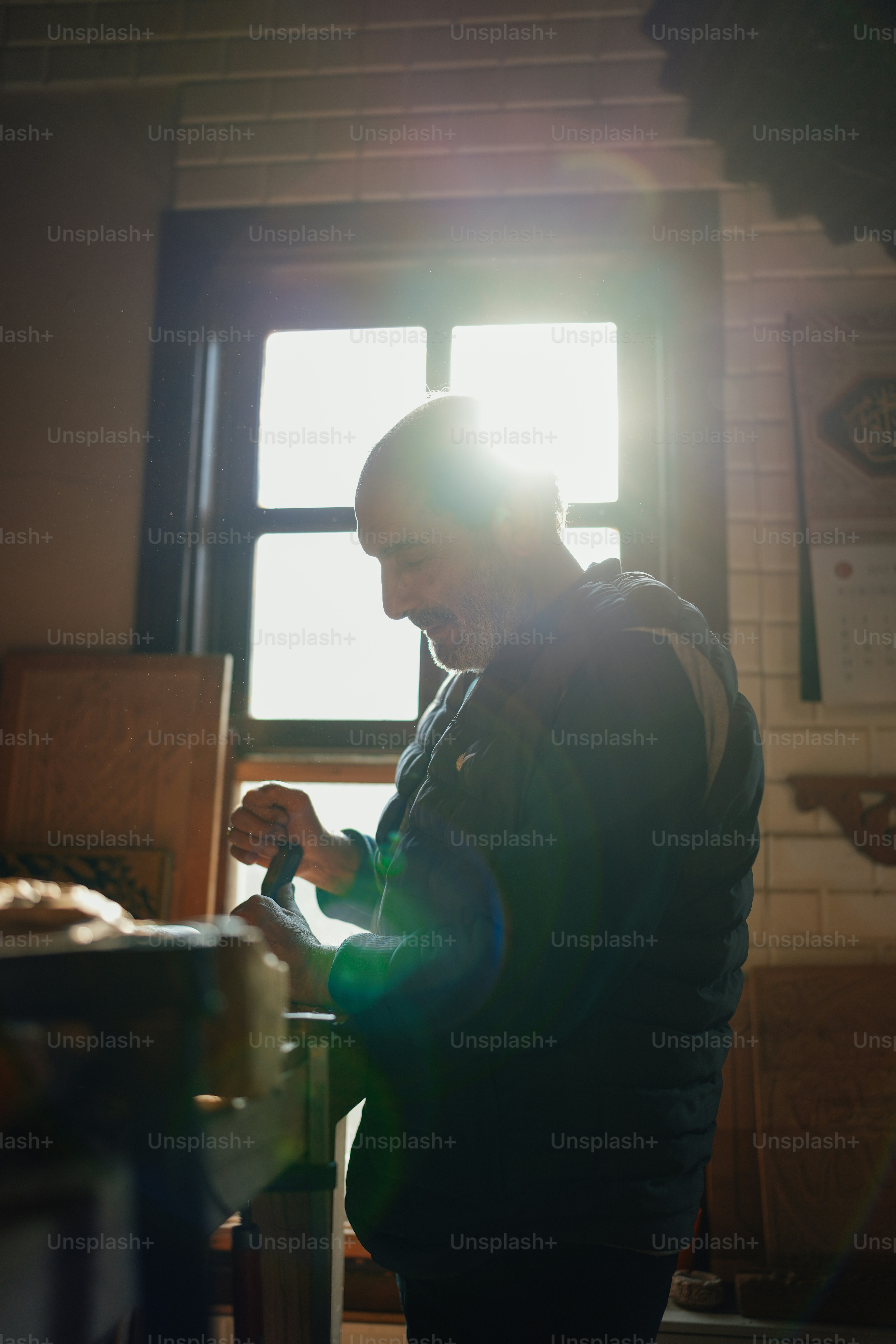 A man in a blue vest is working on a piece of wood photo Hand made