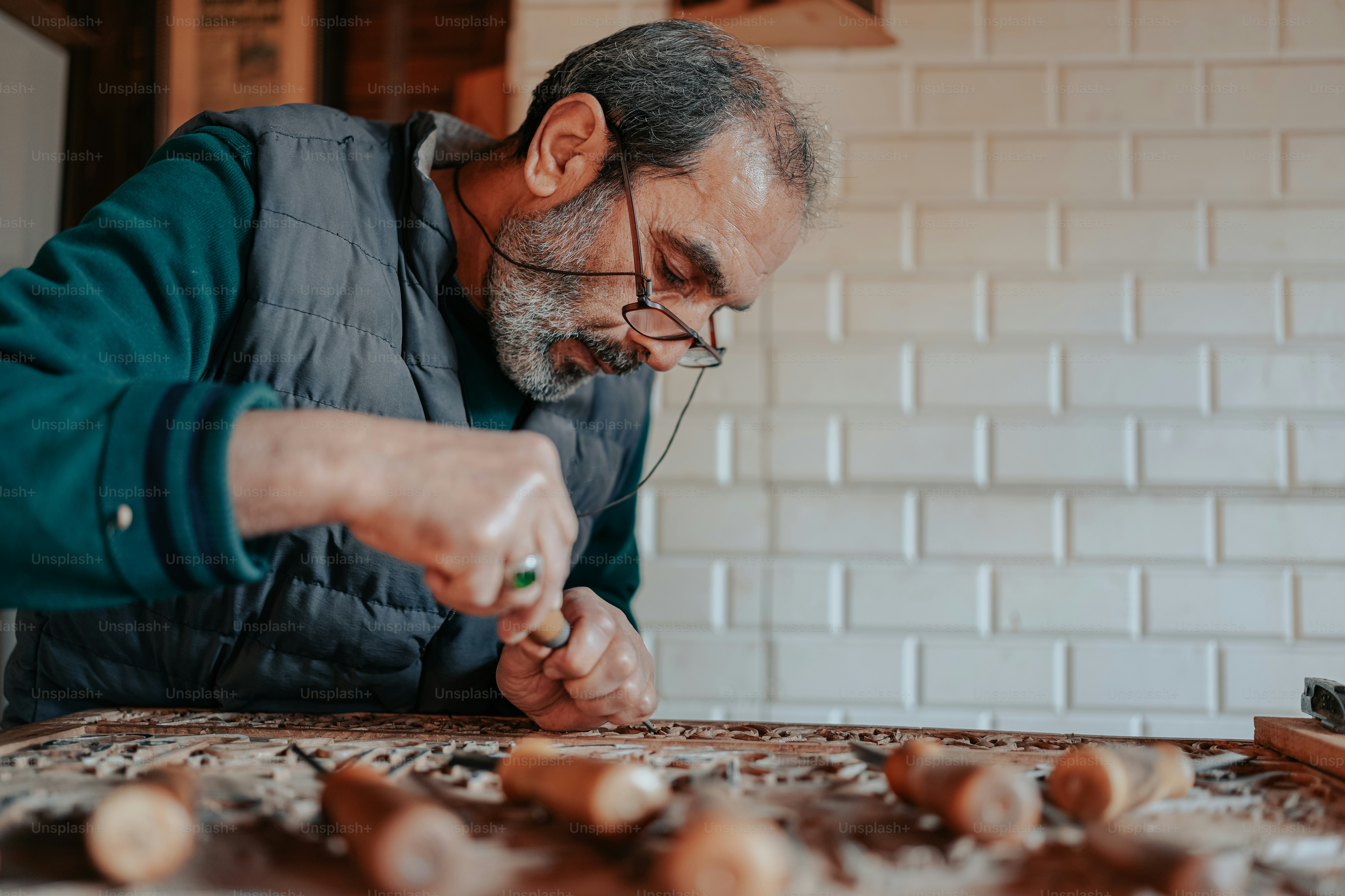 A man in a blue vest is working on a piece of wood photo Hand made