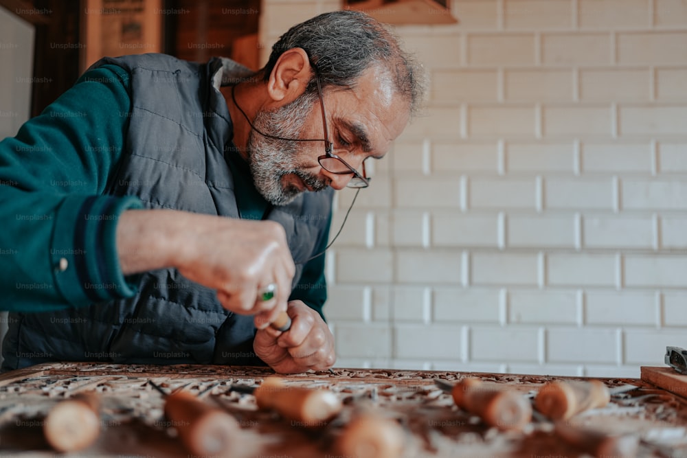 um homem em um colete azul está trabalhando em um pedaço de madeira