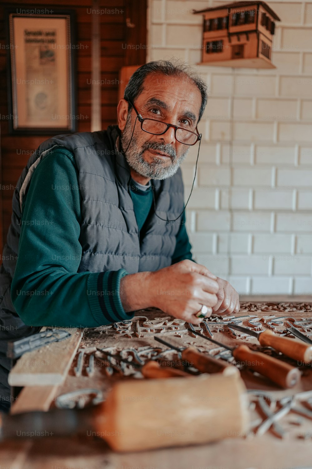 um homem sentado em uma mesa trabalhando em um pedaço de madeira