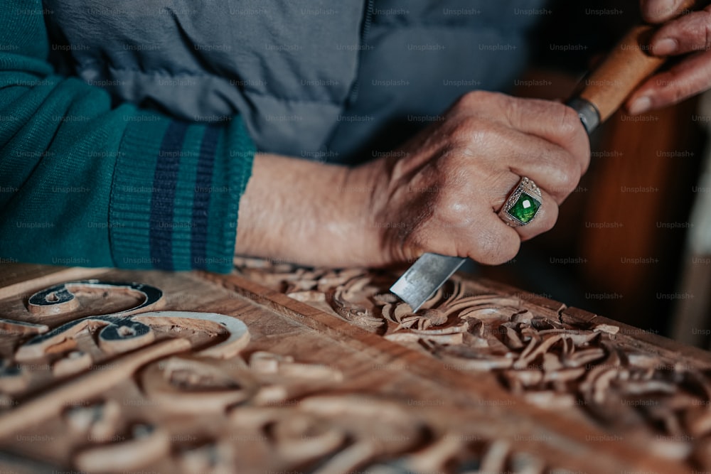 um close up de uma pessoa esculpindo um pedaço de madeira