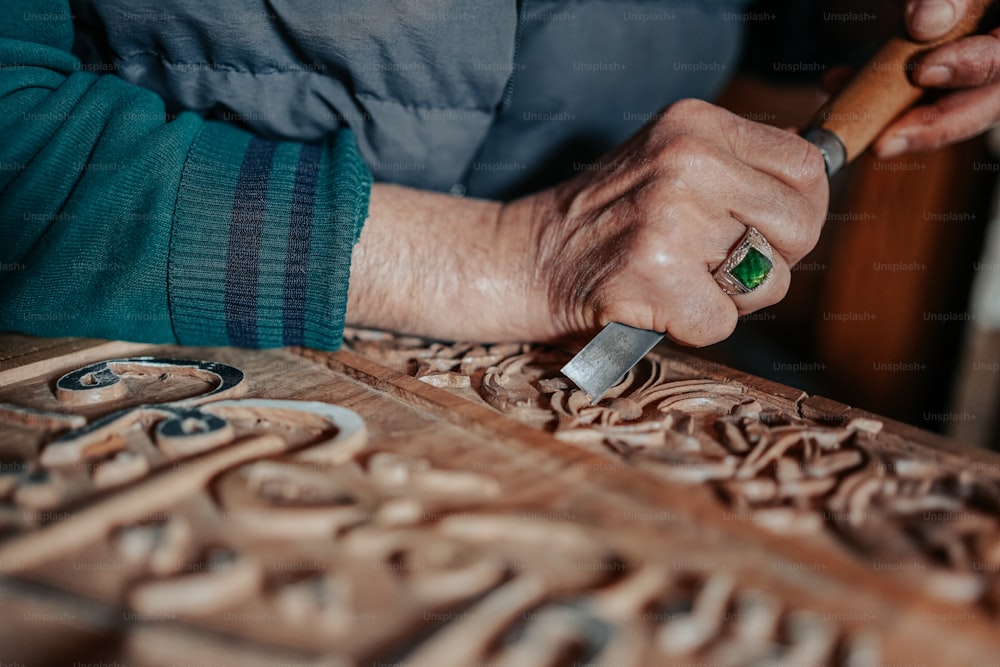 um close up de uma pessoa esculpindo um pedaço de madeira
