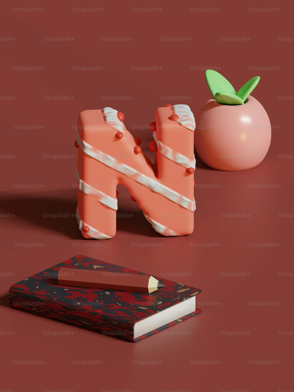 Un libro, un lápiz y una manzana sobre una superficie roja