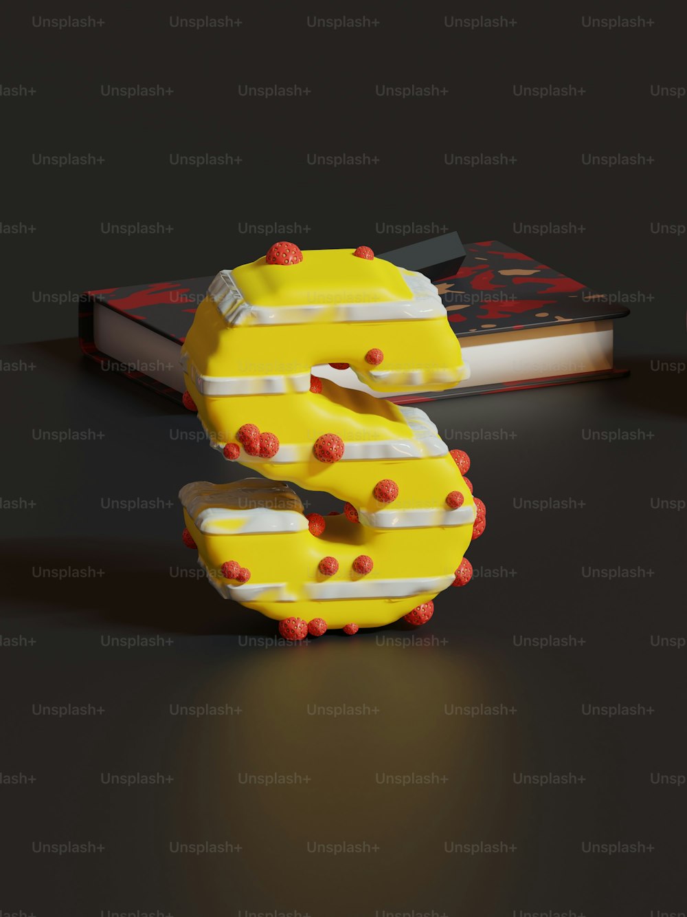 a cake shaped like the letter s sitting next to a book