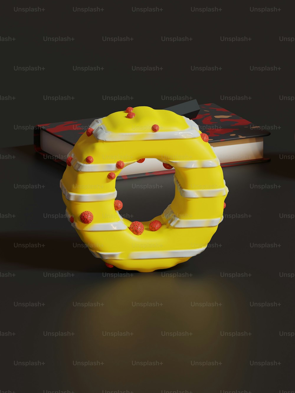 a yellow donut sitting on top of a table next to a book