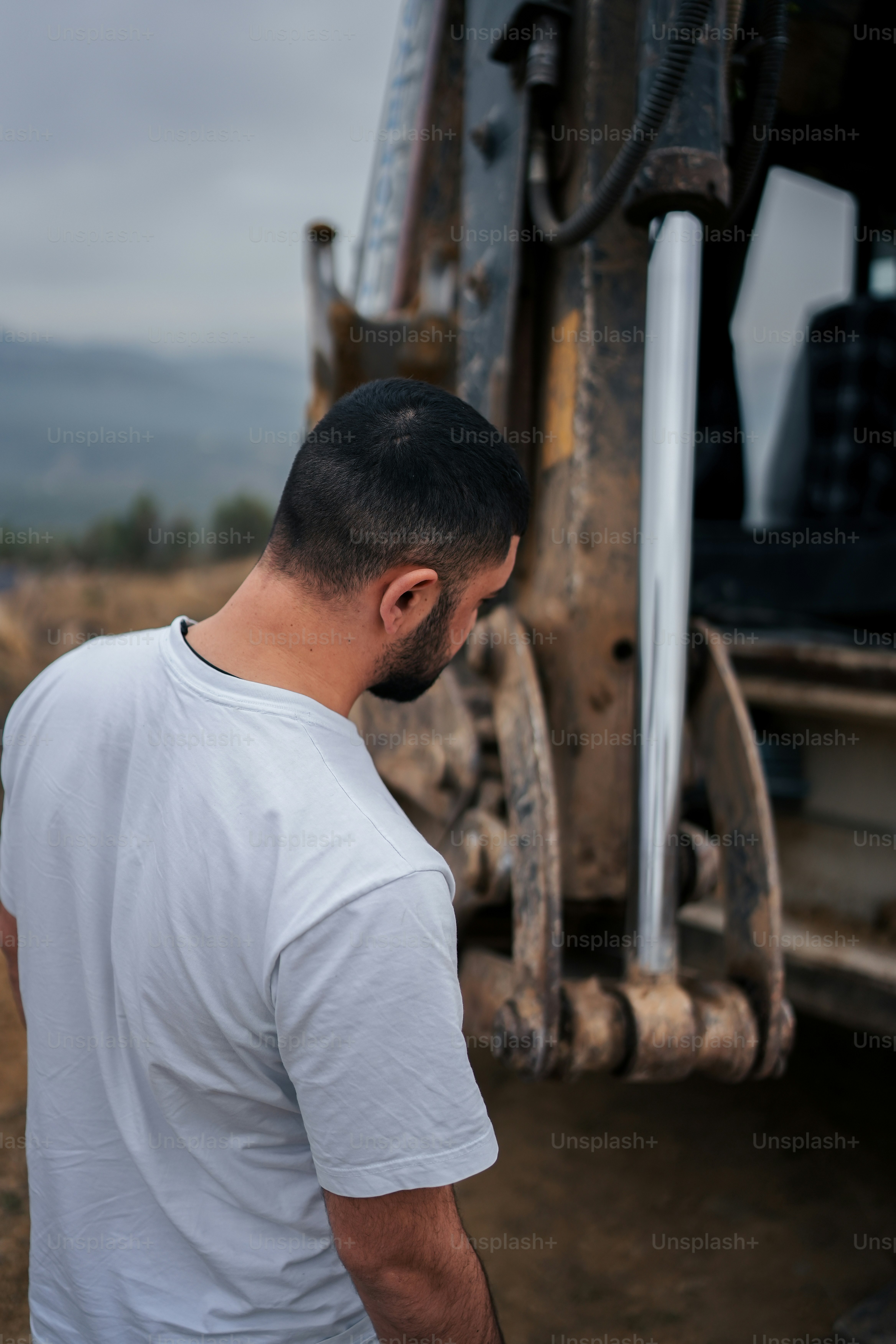um homem em pé na frente de uma escavadeira