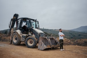 a man standing next to a bulldozer on a dirt road