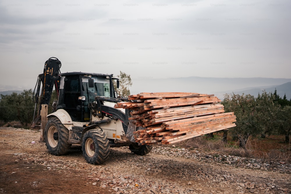 a forklift carrying a load of wood on a dirt road