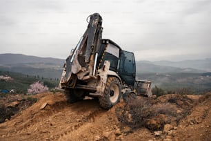 a dump truck on a dirt hill with mountains in the background